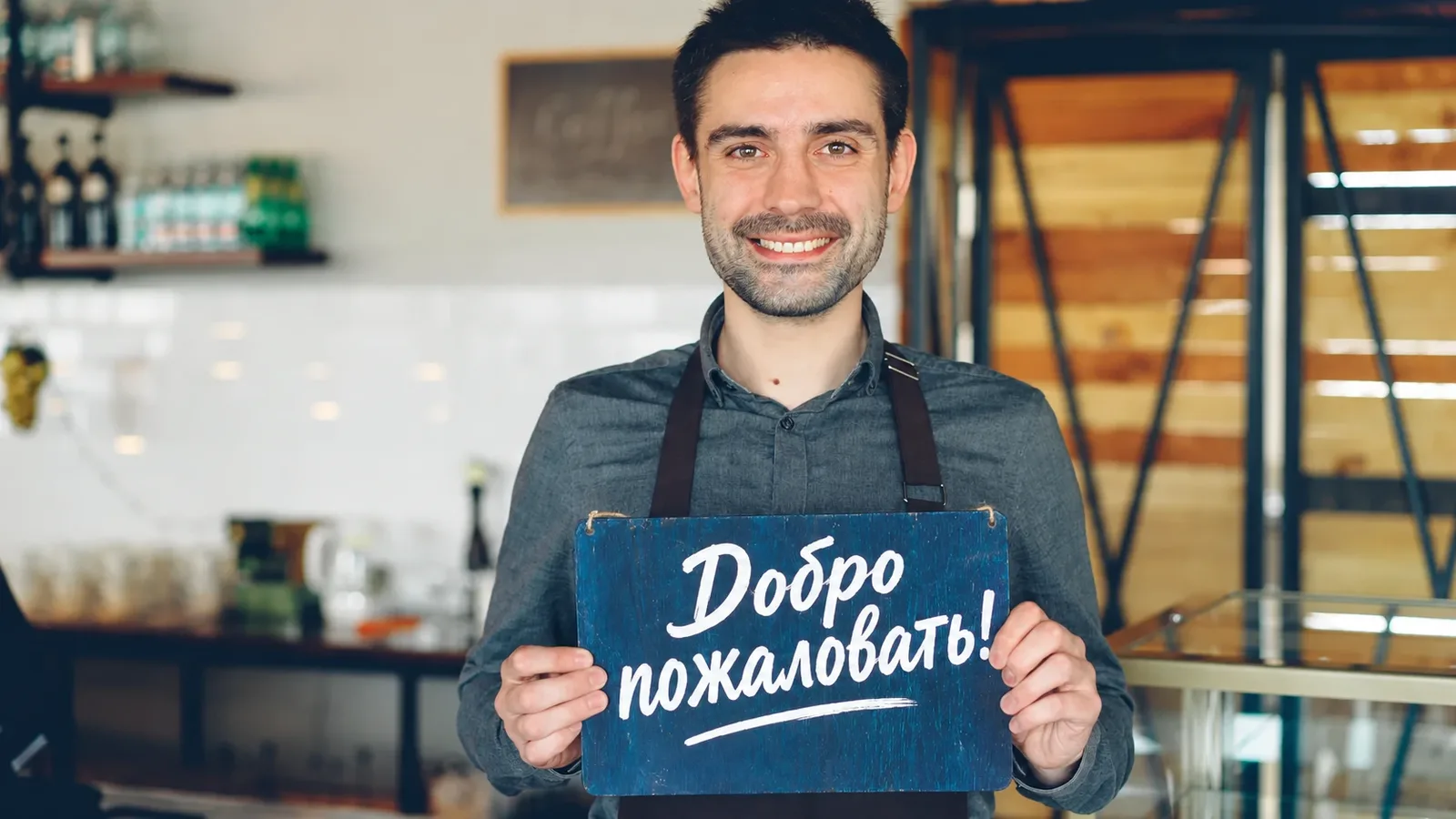 Владелец кофейни с табличкой «Добро пожаловать!»